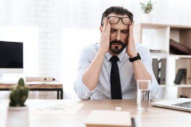 Adam masaya oturur ve ellerini başının üstüne koyar..