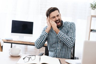 Gömlekli bir adam oturur ve acıdan çığlık atar..