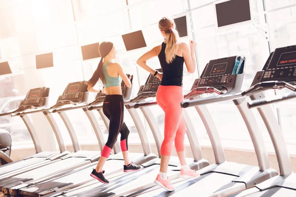 Chicas en ropa deportiva corriendo en una cinta de correr. — Foto de Stock