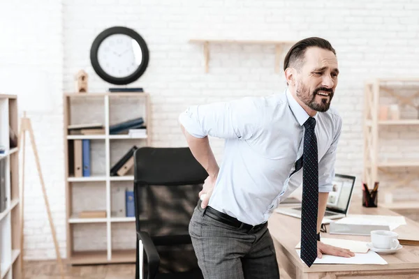 Man in het kantoor pakte zijn pijnlijke rug en lijdt. — Stockfoto