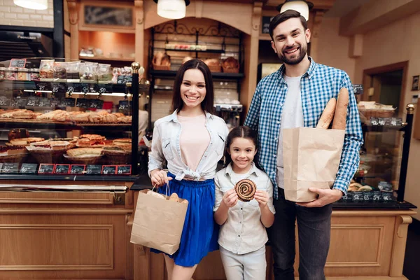 Jong gelukkig gezin koopt brood in de moderne bakkerij. — Stockfoto