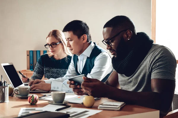 Hombre negro mirando la tableta en su escritorio. — Foto de Stock