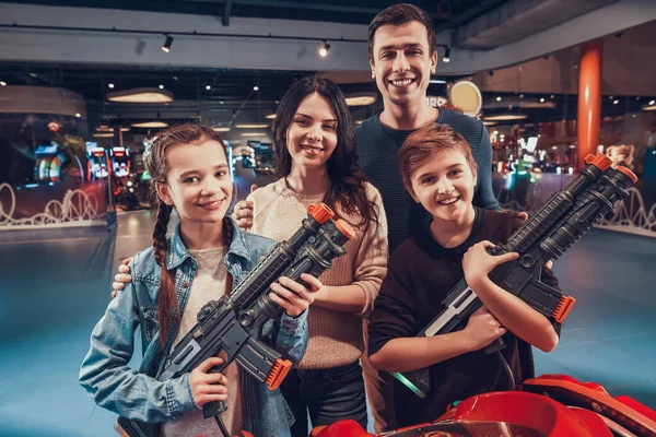 Broder och syster håller leksakspistol nära föräldrar. — Stockfoto