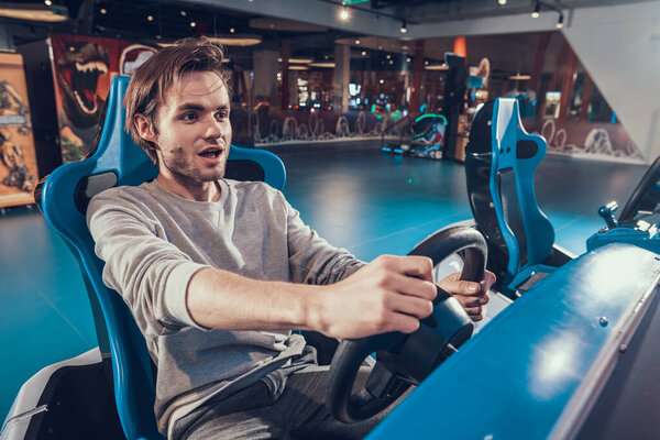 A man sits and holds a toy car behind the wheel.