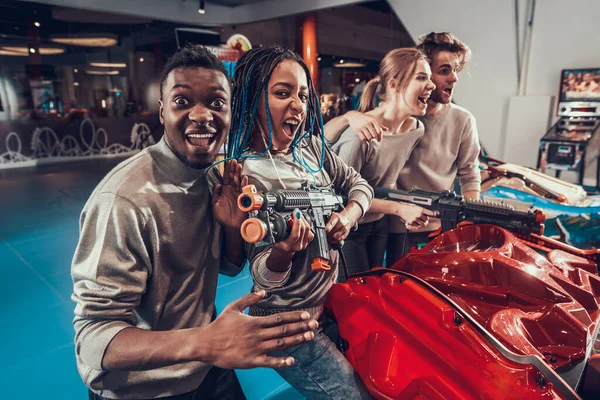 Group of young friends posing with guns in arcade. — Stock Photo, Image