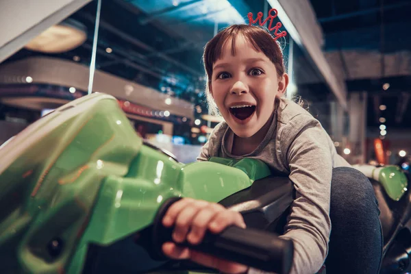 Una chica conduce un paseo en moto de juguete. —  Fotos de Stock