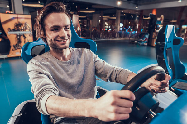 Man smiles while driving a game car. 