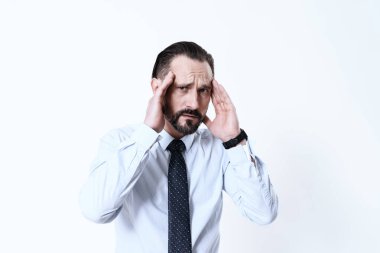 Kravatlı ve gömlekli bir adam acı çeken bir yüzle ayakta duruyor..