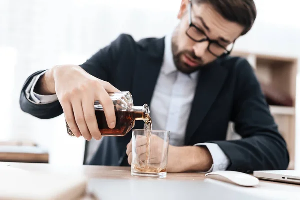Hombre bebiendo una bebida alcohólica en el lugar de trabajo. —  Fotos de Stock