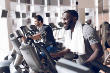 Modern spor salonunda iki adam koşu bandında..