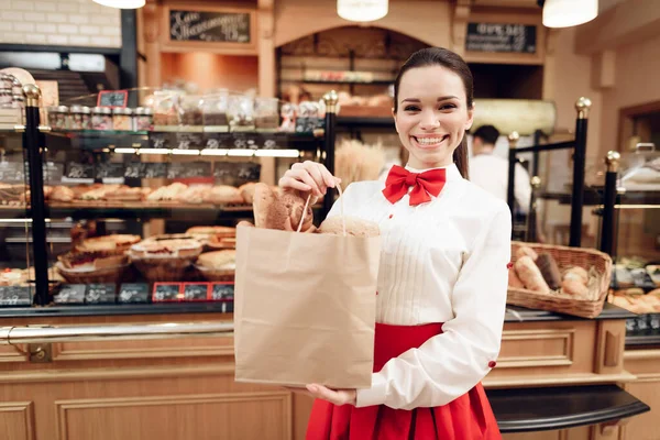 Mladá usmívající se žena stojící s chlebem v pekárně. — Stock fotografie
