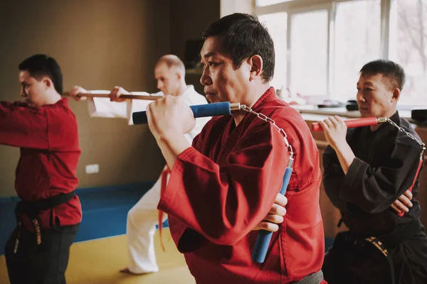 A man works out tricks with nunchucks in the gym.