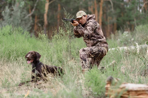Caza perro persiguiendo conejo hombre con rifle apuntando. — Foto de Stock