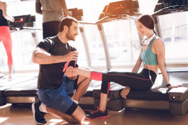 Antrenör spor salonunda bir kızın bacağını esnetir..