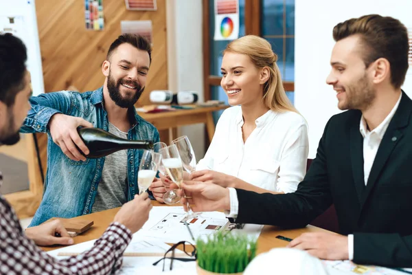 Man schenkt collega 's een champagne aan tafel op het werk. — Stockfoto