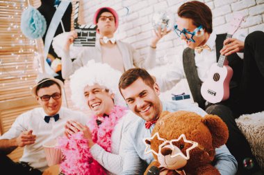 Bir adam ayıya gözlük takar ve kameraya gülümser..