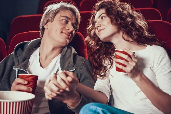 Любляча пара сидить тримаючи руки в кіно . — стокове фото