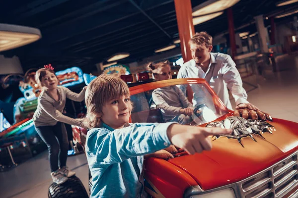 Papá está cerca de su hija que conduce un coche de juguete. —  Fotos de Stock