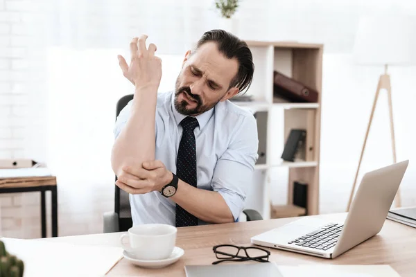 Ένας άνδρας στο χώρο εργασίας αισθάνεται πόνο στο χέρι του. — Φωτογραφία Αρχείου