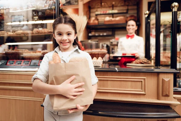 Jong lachend meisje kopen brood in moderne bakkerij. — Stockfoto