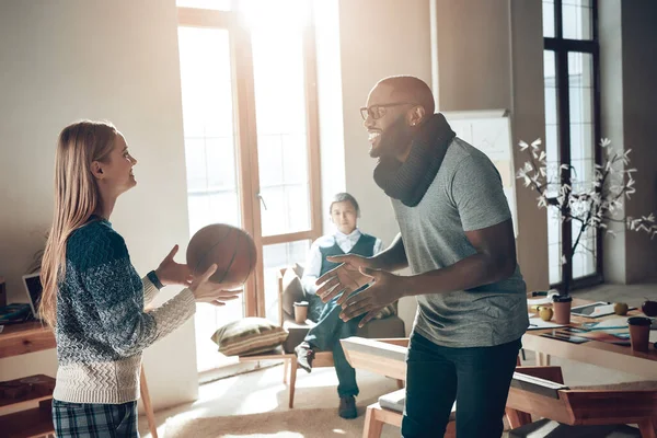 Multinational company plays basketball in office.