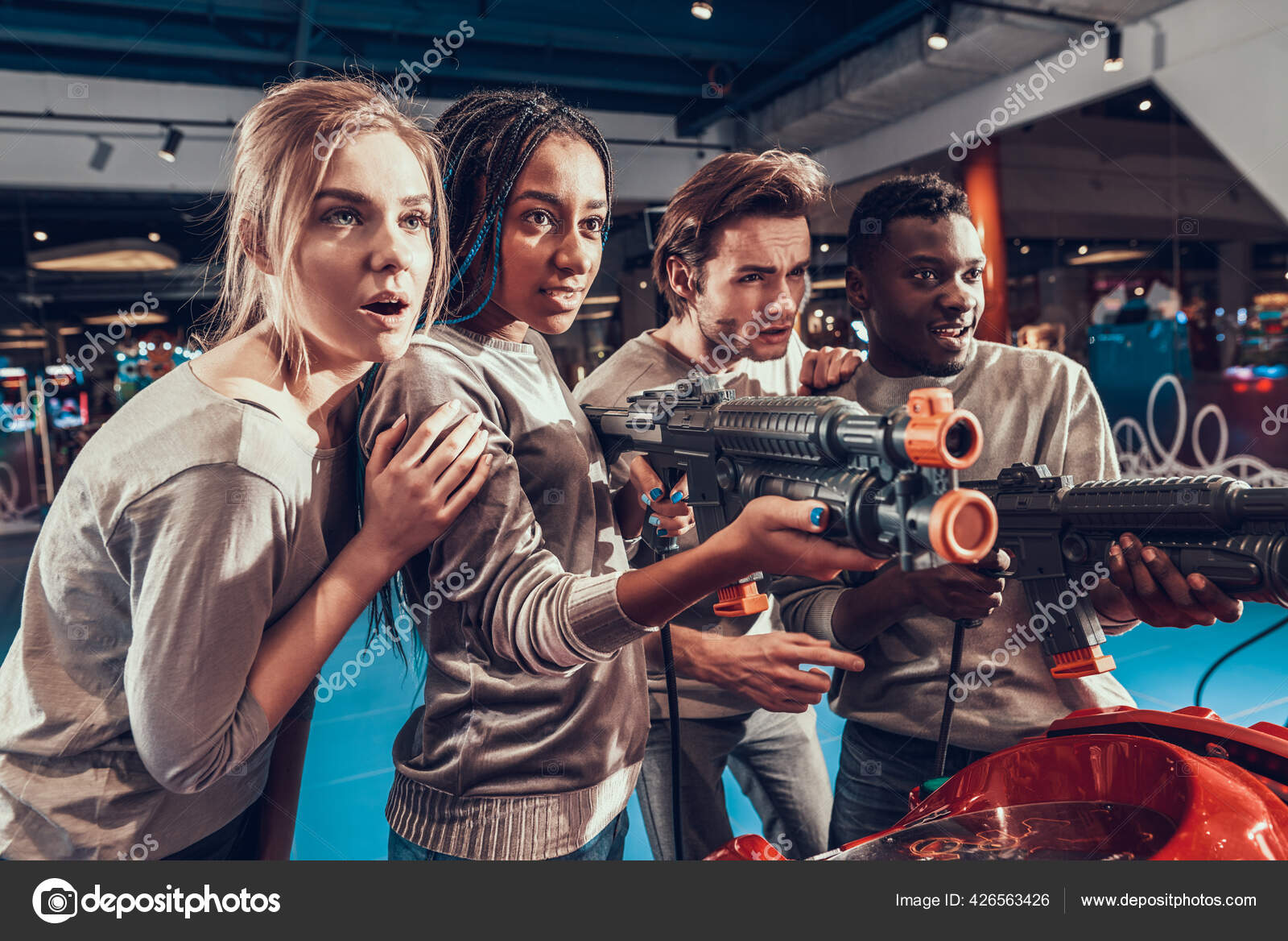 Group of young friends shooting guns in arcade