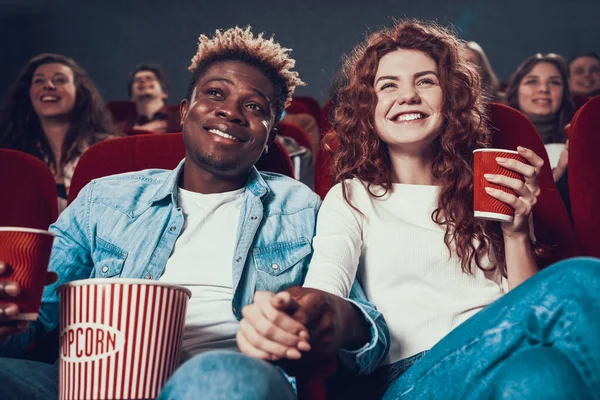 Jeune couple assis au cinéma et se tenant la main. — Photo