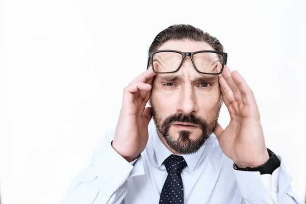 Een man met een baard kijkt naar de camera en voelt migraine. — Stockfoto