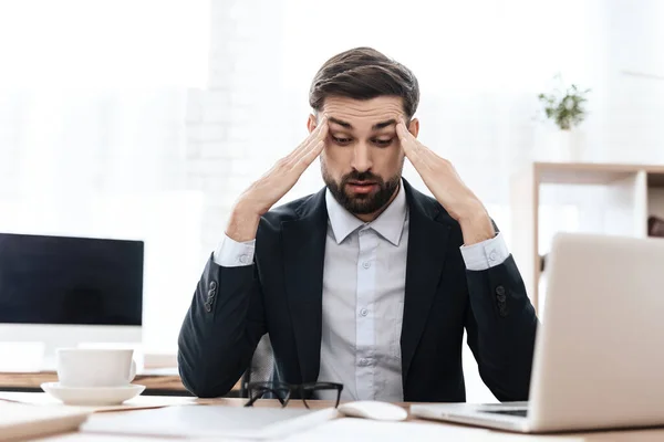 Un hombre se sienta en una mesa y siente un dolor severo. — Foto de Stock