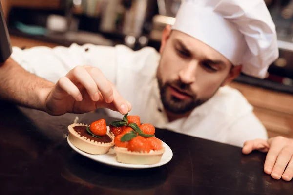 Jonge baard man met taart staande in de bakkerij. — Stockfoto