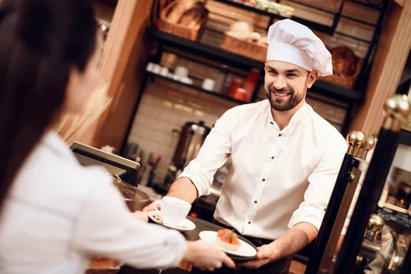 Jongeman verkoopt cake en thee aan vrouw in de bakkerij — Stockfoto