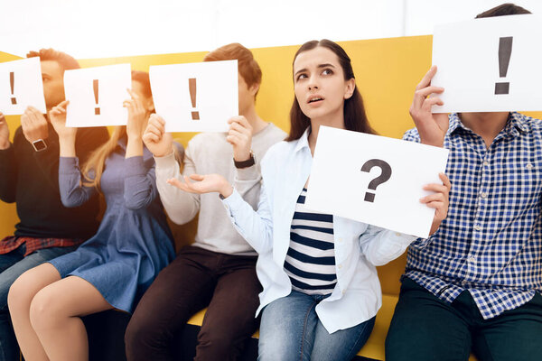 Puzzled girl holds sheet with image question mark.