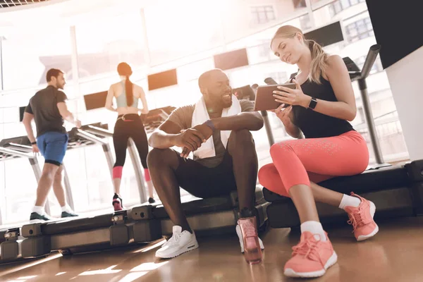 Chica muestra algo a un chico en una tableta en el gimnasio. — Foto de Stock