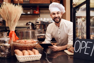 Önlüklü Genç Sakallı Adam Pastanede duruyor.