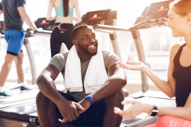 Bir adam spor salonunda bir kızla konuşuyor ve gülümsüyor..