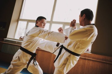 Bir adam ayakta dururken bir Çinlinin karnına vuruyor..