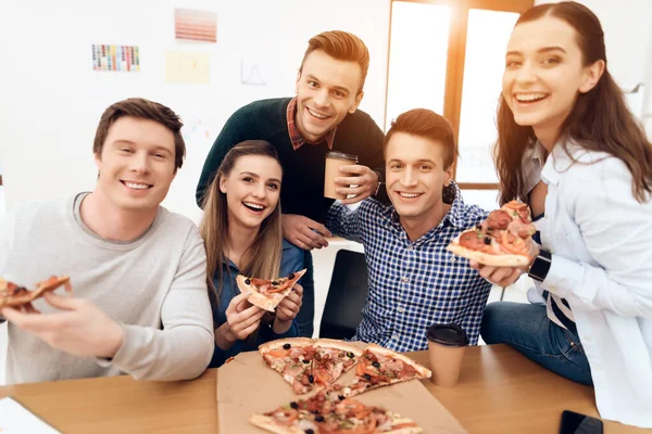 Люди едят вкусную пиццу и смотрят в камеру.. — стоковое фото