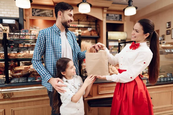 Jong gelukkig gezin koopt brood in de moderne bakkerij. — Stockfoto