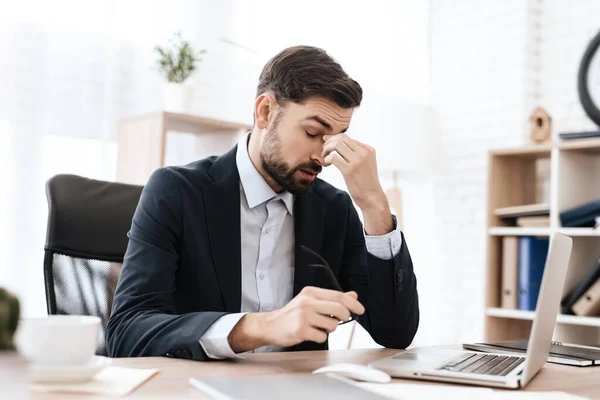 Un uomo si siede ad una scrivania ed è stanco di lavorare. — Foto Stock