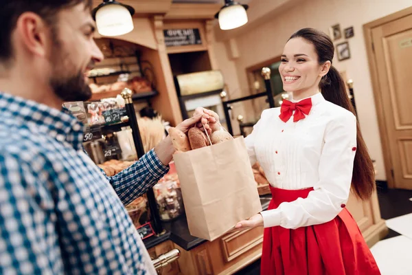Glimlachend meisje geven pakket met brood naar de man. — Stockfoto