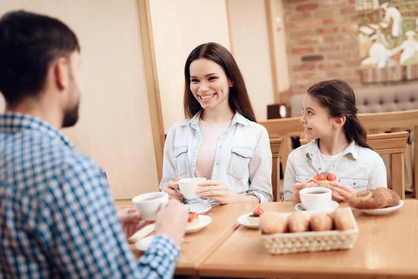 Junge glückliche Familie isst Kuchen in Cafeteria. — Stockfoto