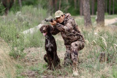 Tüfekli köpekle nişan alan adam sessizce oturuyor..