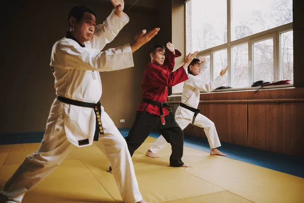 The coach teaches his students karate in the gym.