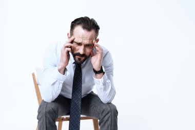 Gömlekli bir adam acıdan sandalyede oturuyor..