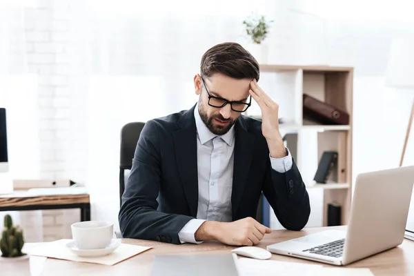 Un hombre se sienta en un lugar de trabajo y siente incomodidad. — Foto de Stock