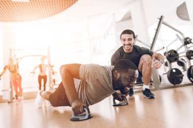 Antrenör, öğrencileri spor salonunda destekliyor ve gülümsüyor.. 