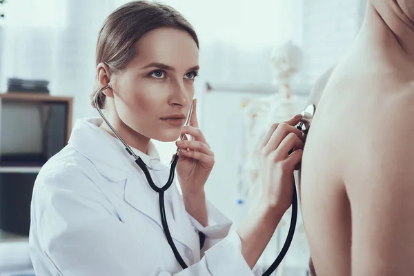 Dokter onderzoekt en luistert naar de patiënt. — Stockfoto