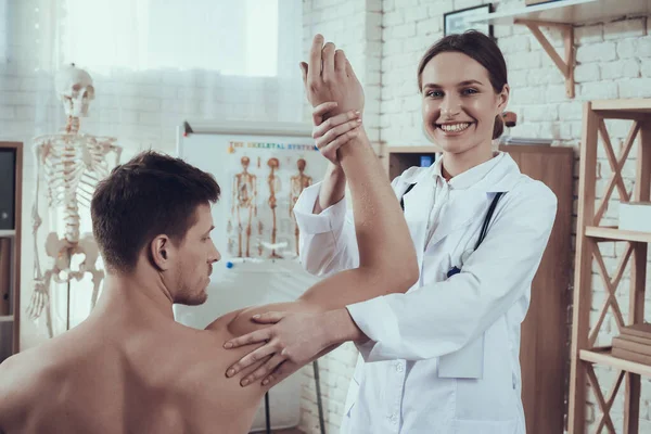 Vrouwelijke arts met stethoscoop in functie. Dokter onderzoekt atleten arm. — Stockfoto