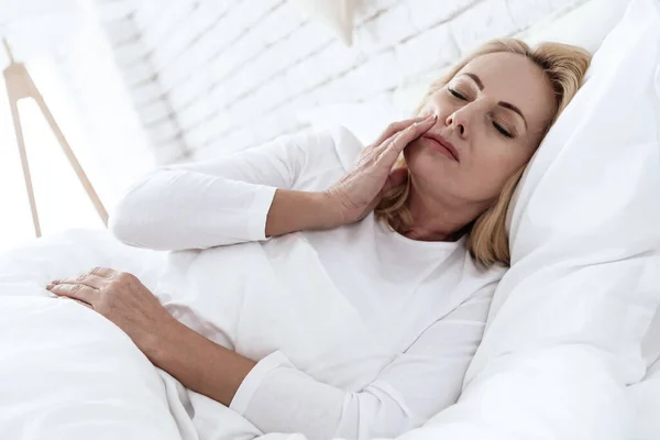Mujer en cama blanca con dolor intenso en los dientes. — Foto de Stock