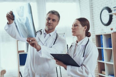 Erkek doktor muayenehanede kadının röntgenini gösteriyor.. 